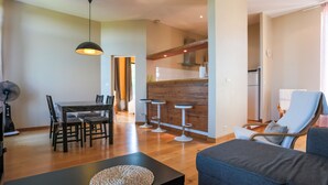 A modern living room with a dining area, a kitchen in the background, and a balcony with a chair. - Résidence du Chateau de Bégué (Cazaubon)