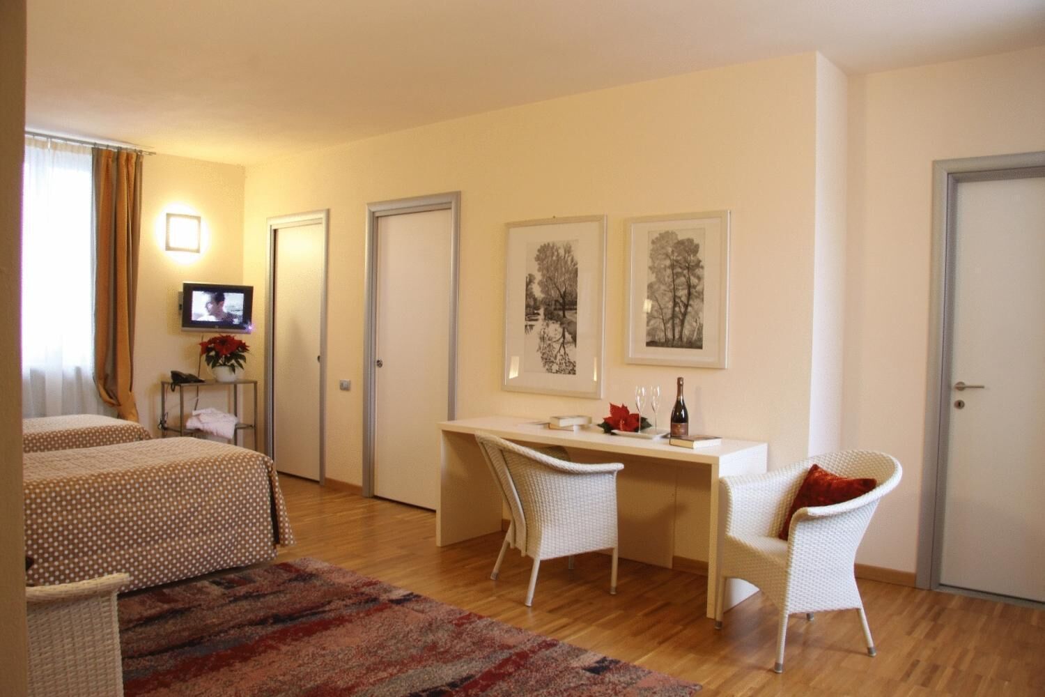 A hotel room with two beds, a desk, a chair, a television, and artwork on the wall.