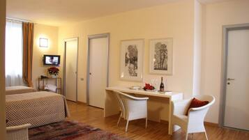 A hotel room with two beds, a desk, a chair, a television, and artwork on the wall.