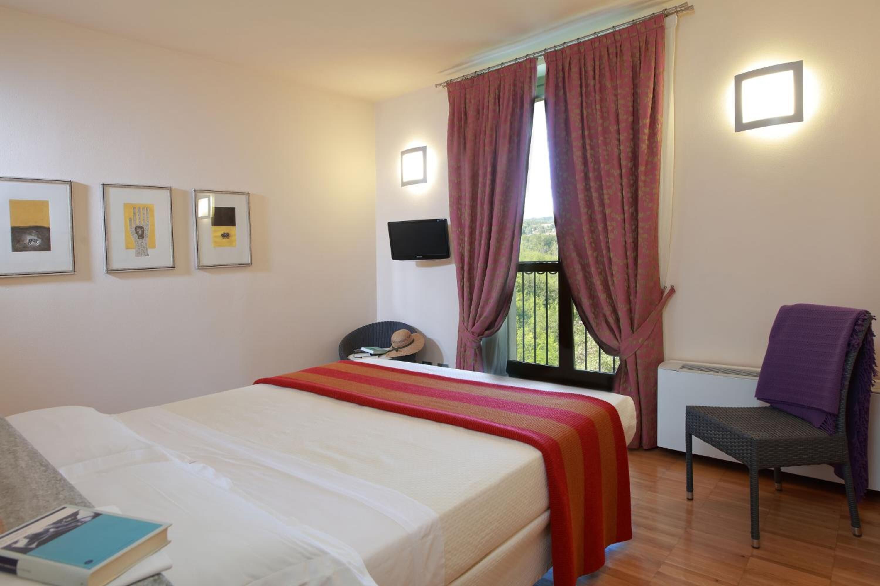 Ein Schlafzimmer mit Bett, Stuhl, Schreibtisch und einem Fenster mit Vorhängen.