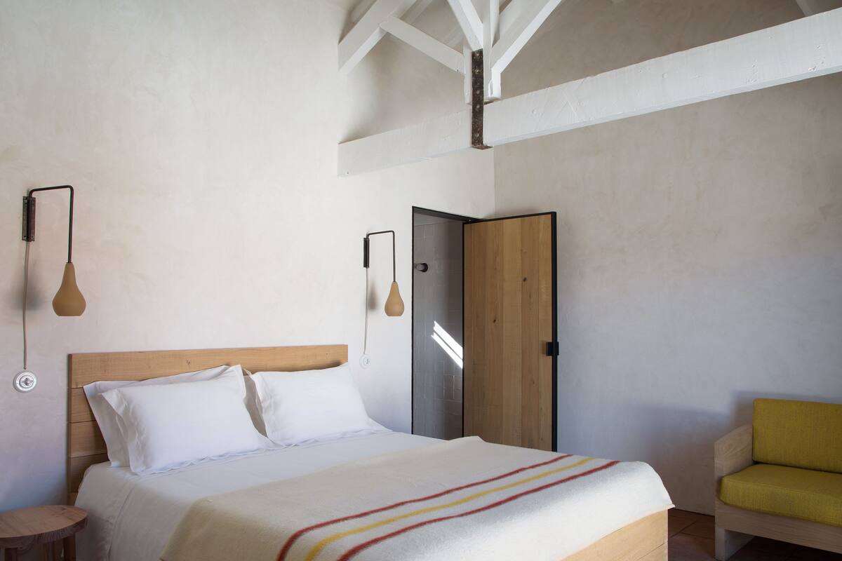 Une chambre à coucher avec un lit en bois, une table de chevet, une chaise jaune et une armoire.