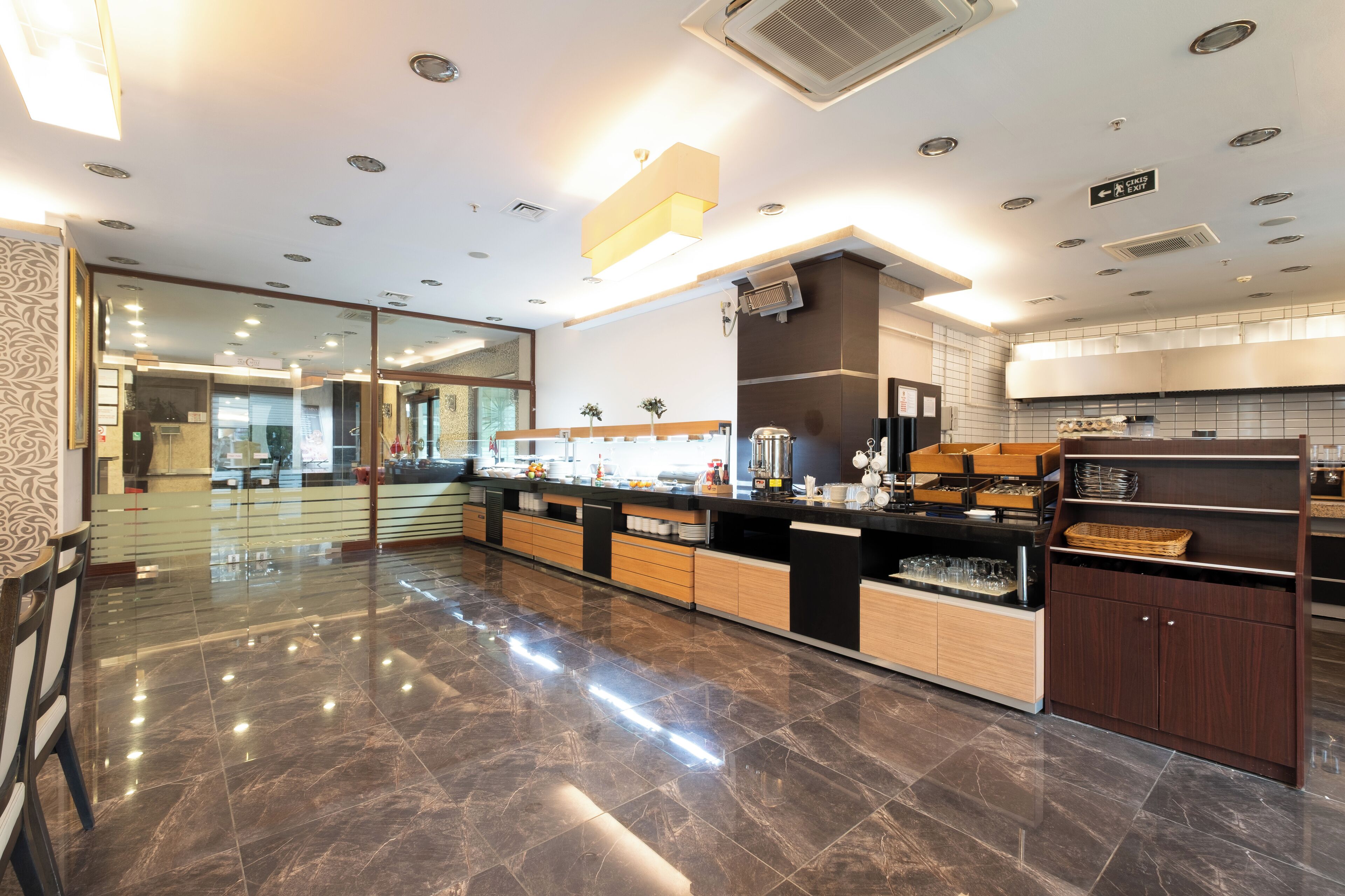 A modern hotel lobby with a polished marble floor, a reception desk, and a buffet area.