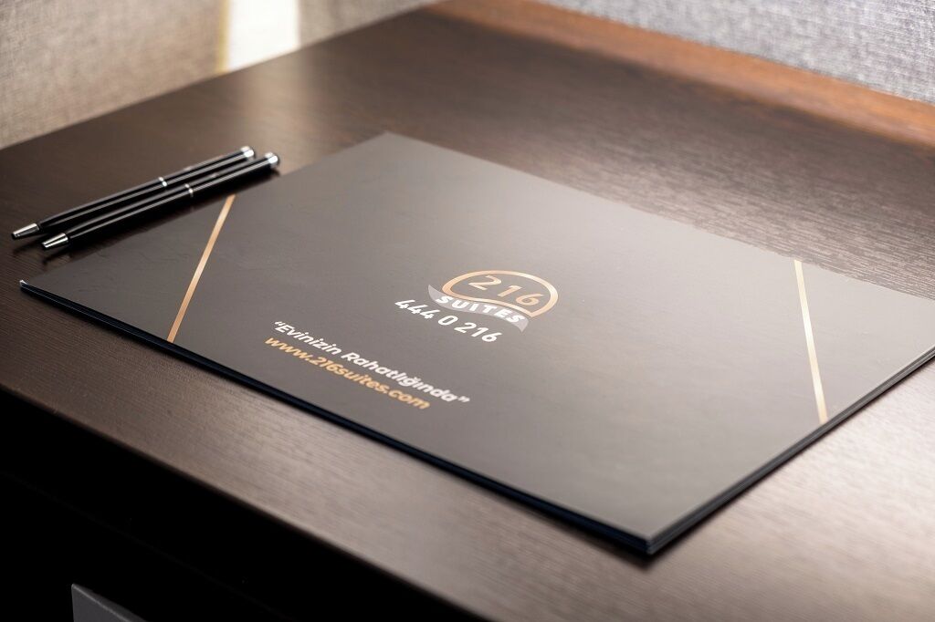A black folder with gold accents and text, placed on a wooden surface.