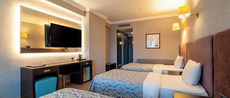 Una habitación de hotel con dos camas, un escritorio con computadora, televisión y baño.