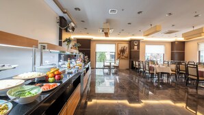 Un bufé con diversas opciones de comida, un área de estar con mesas y sillas, y una decoración interior moderna.