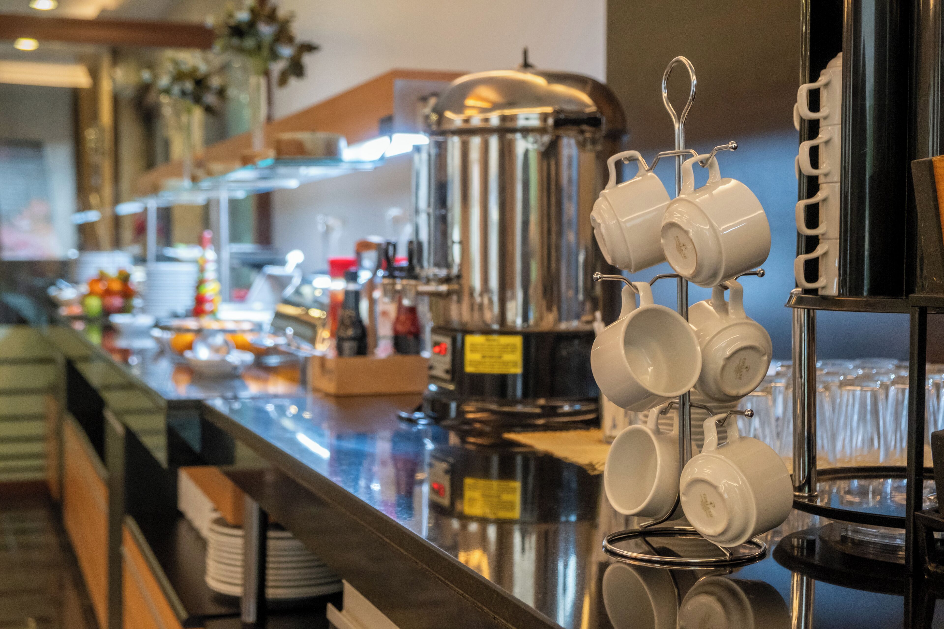 A buffet area with a coffee station, including a coffee pot, cups, and a coffee maker.