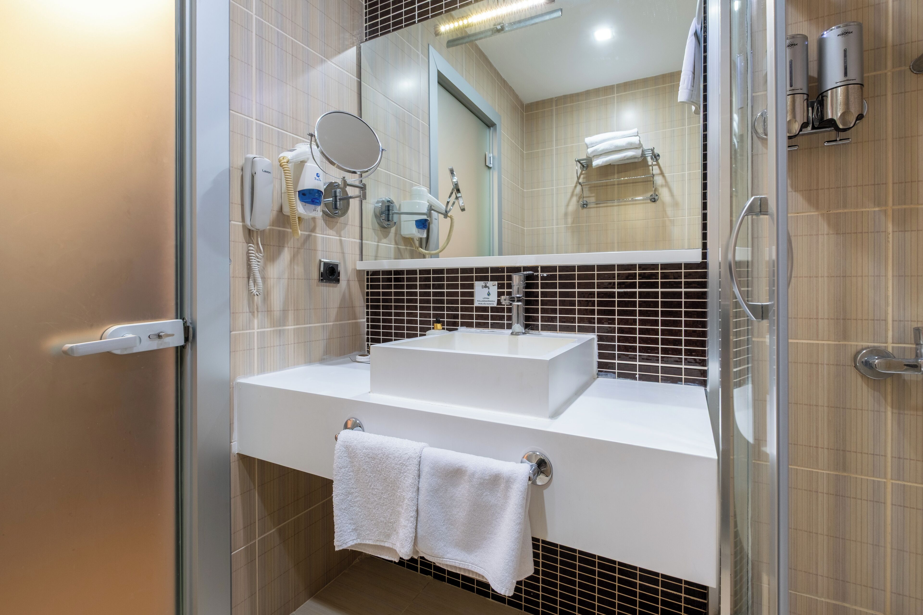 A modern bathroom with a glass shower door, a white sink, and a mirror.
