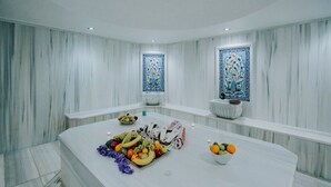 Un baño moderno con tocador de mármol, frutero y azulejos decorativos.