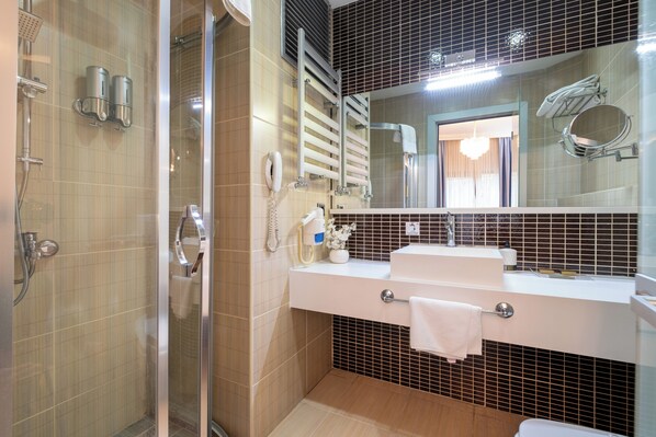 A modern bathroom with a glass shower enclosure, a white sink with a towel rack, and a large mirror above the sink. - 216 Castle Hotel (Gebze)