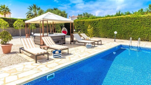 A swimming pool with lounge chairs and a covered seating area. - Villa Siesta (Pegeia)
