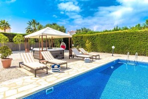 A swimming pool with lounge chairs and a covered seating area. - Villa Siesta (Pegeia)