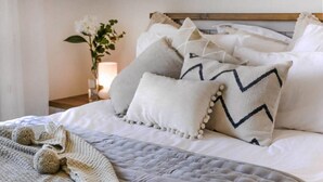 A neatly made bed with a quilted cover, multiple pillows, and a knitted throw. - Villa Siesta (Pegeia)