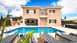 Una casa de dues plantes amb piscina, zona d'estar a l'aire lliure i barbacoa.