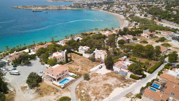 Vista aèria d'una zona residencial a la costa, amb cases, una piscina i una platja.