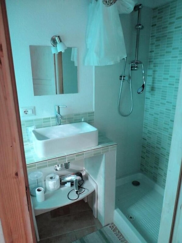 A bathroom with a white sink, mirror, and shower.