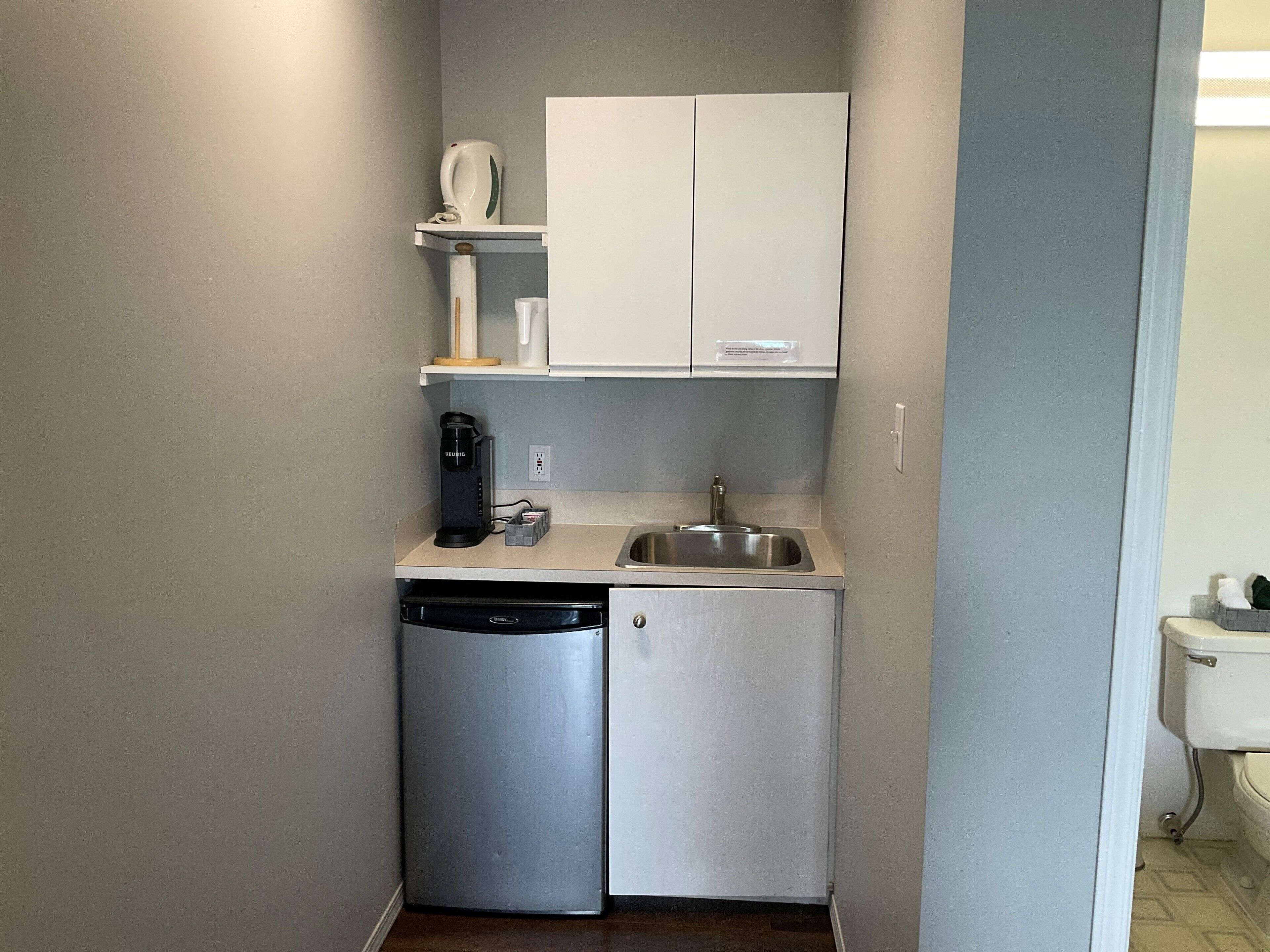 A compact kitchenette with a dishwasher, a coffee maker, and a sink.