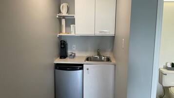 A compact kitchenette with a dishwasher, a coffee maker, and a sink.