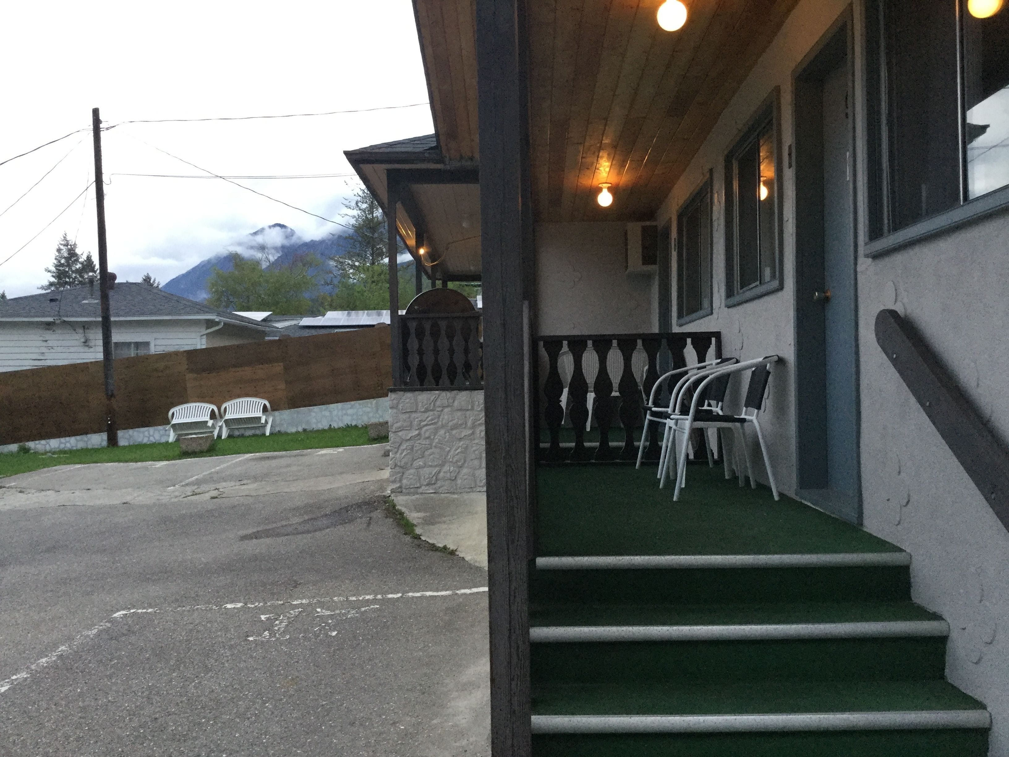 A building with a wooden porch, outdoor seating, and a staircase leading to the entrance.