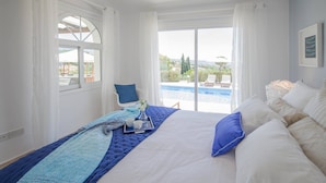 A bedroom with a large bed, a view of a swimming pool, and a balcony. - Villa Luna (Pegeia)
