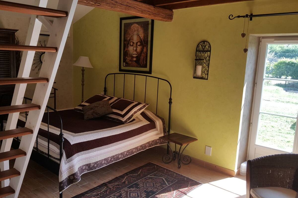 Un dormitorio con cama, una silla, una lámpara, un cuadro y una ventana.