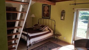 Una camera da letto con un letto, una sedia, una lampada, un quadro e una finestra.