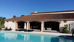 Ein Poolbereich mit Flachdach, Liegestühlen und einer überdachten Sitzgelegenheit.