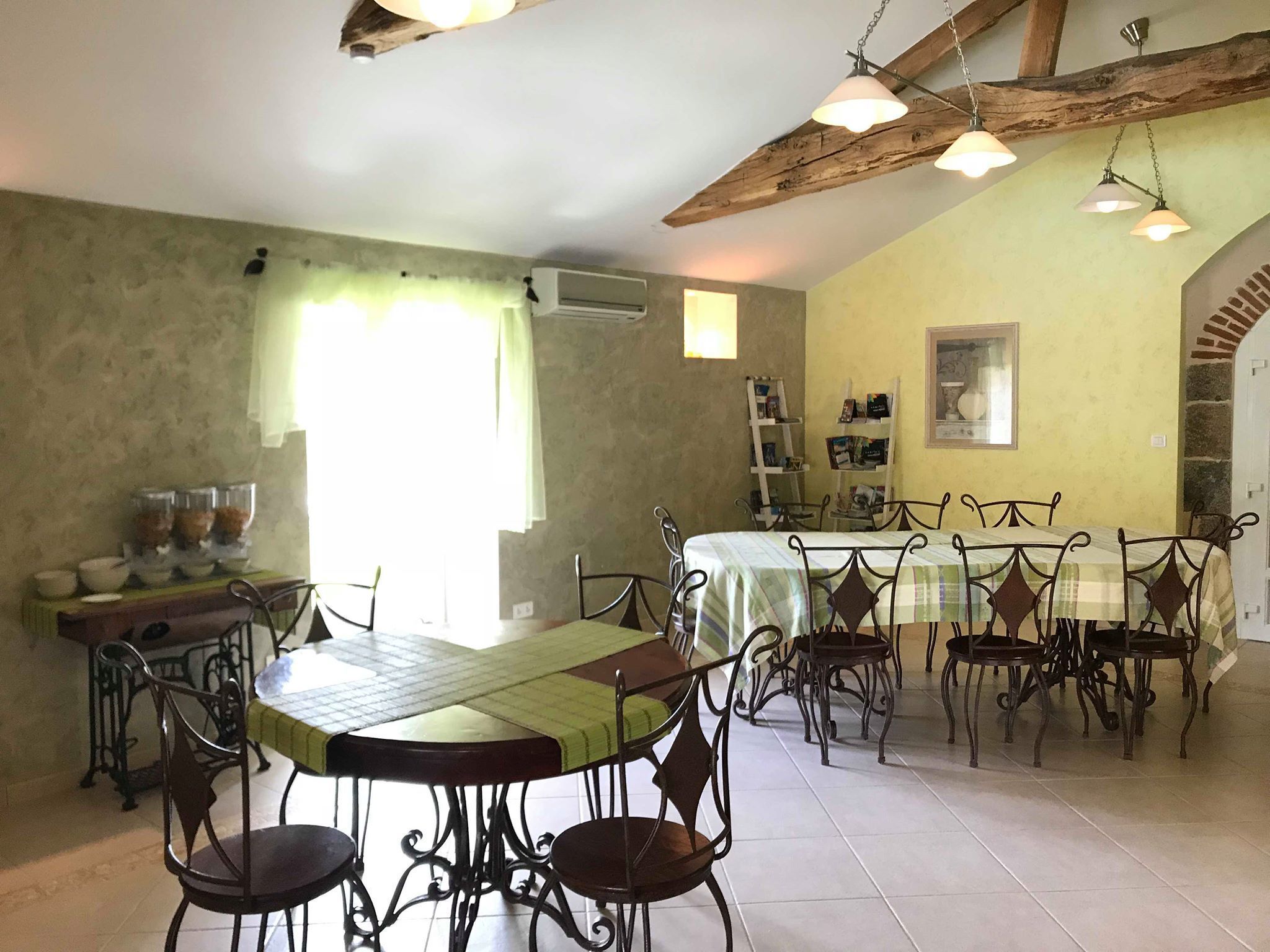 A dining area with a large table, chairs, and a high ceiling with exposed beams.