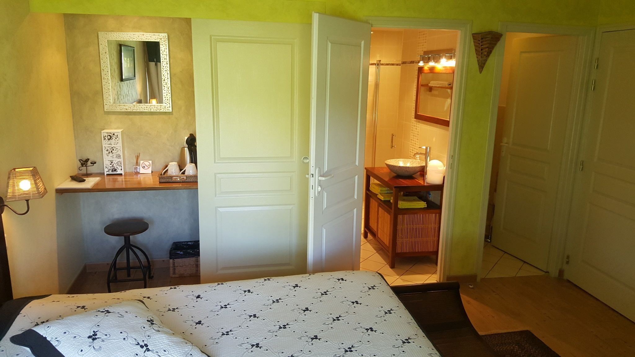 Quarto com cama, escrivaninha com cadeira, espelho e banheiro com pia e espelho.
