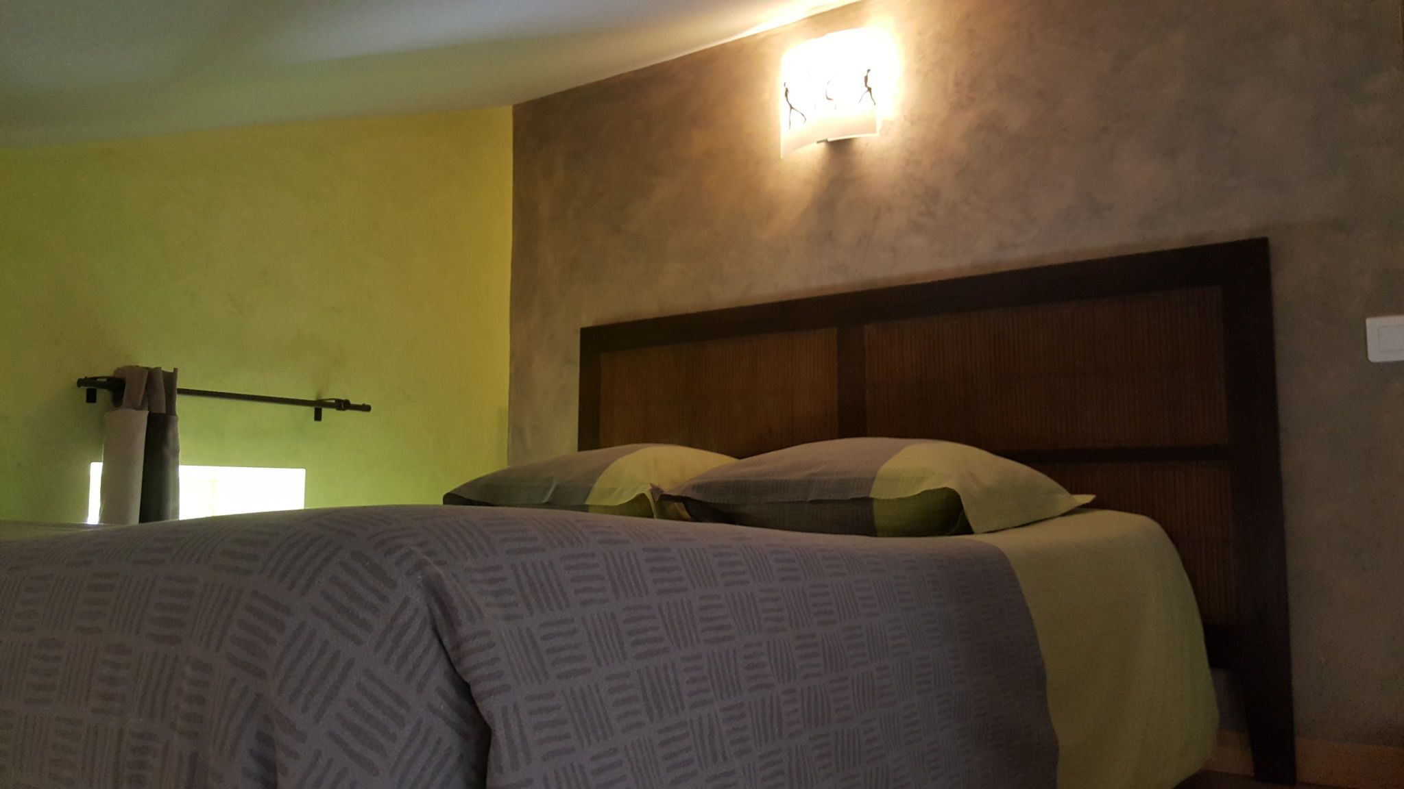 A bedroom with a bed, a headboard, and a wall-mounted light fixture.