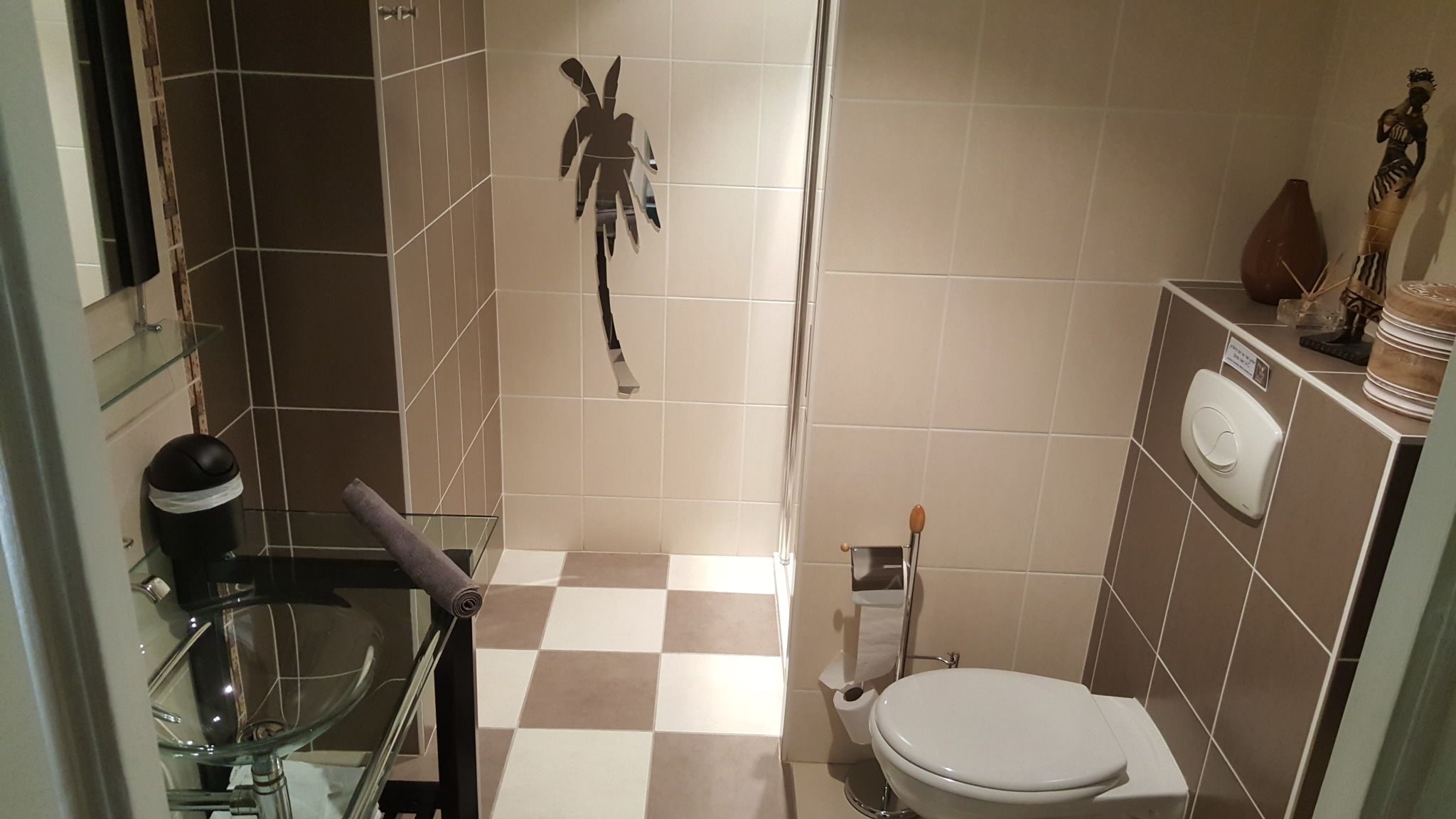 A compact bathroom with a toilet, bidet, and glass sink.