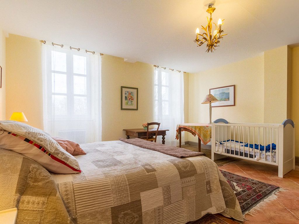 Un dormitorio con cama, cuna, mesa y silla.
