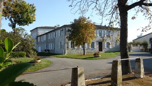 Un bâtiment en pierre doté d’une façade symétrique, d’une entrée centrale et d’une allée pavée.