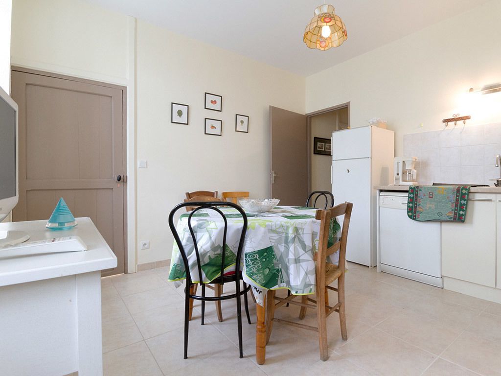 A compact kitchen with a dining table, chairs, a refrigerator, and a microwave.