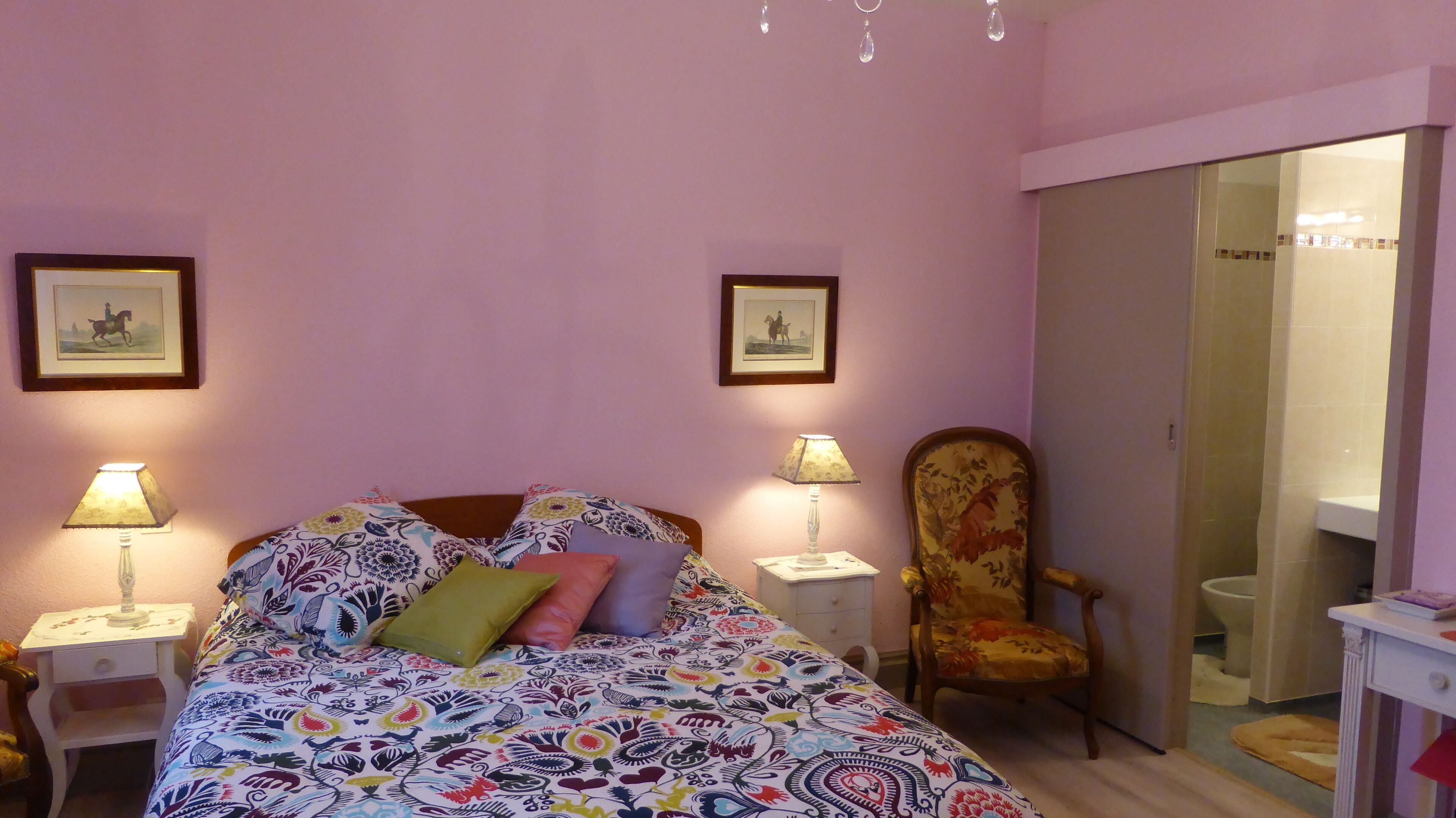 A bedroom with a bed, two bedside tables with lamps, a chair, and a mirror.