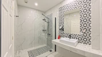 Un baño moderno con ducha, lavabo y espejo.