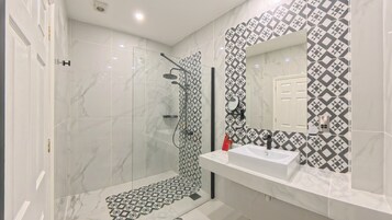 Un baño moderno con ducha, lavabo y espejo.