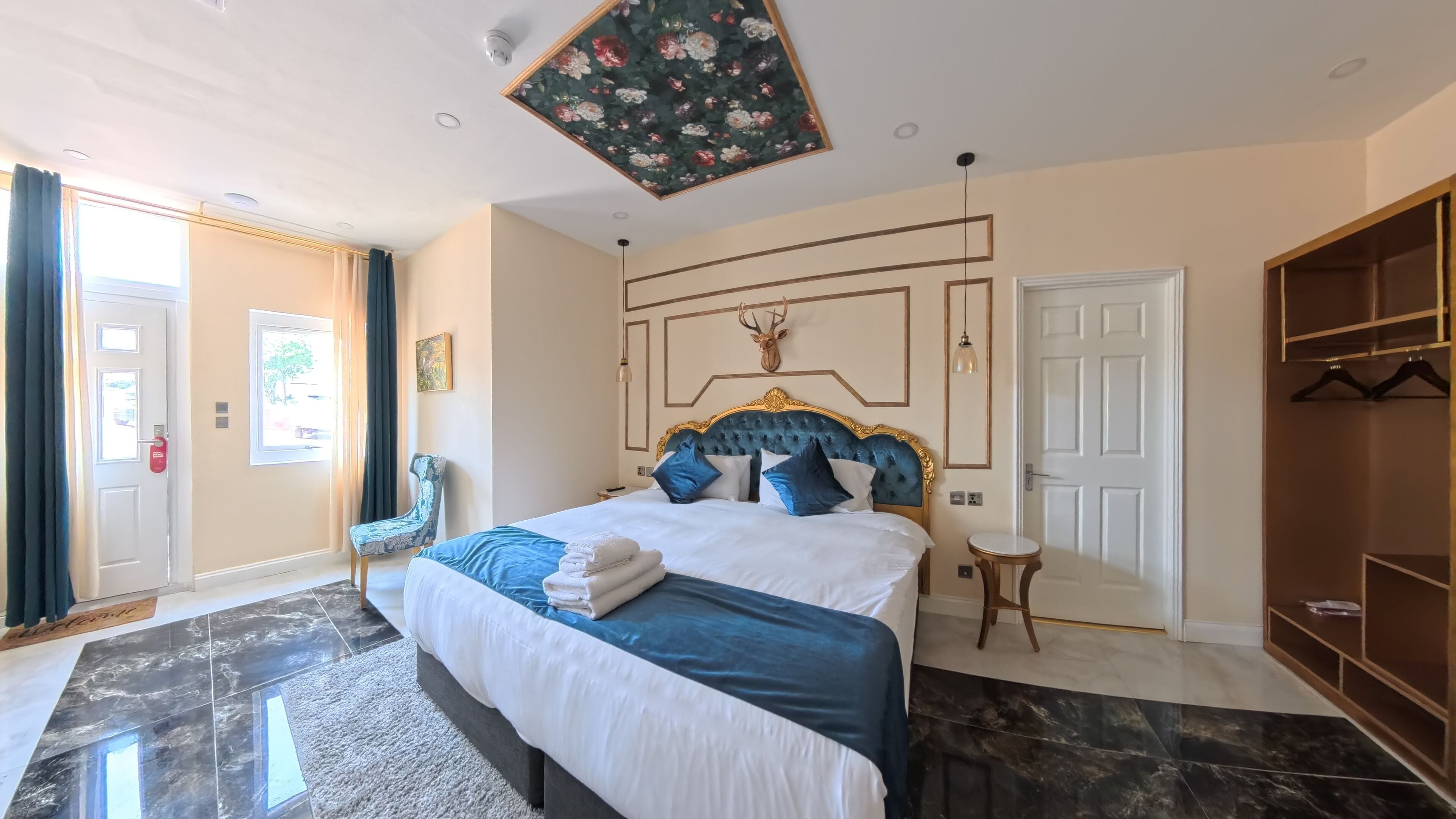 Una camera da letto con un letto grande, un poggiatesta con un corno di cervo, un armadio e un quadro a soffitto.