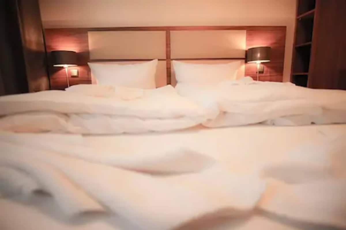 A neatly made bed with white linens in a hotel room.