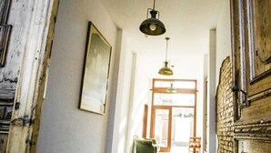 A hallway with a wooden door, a green chair, and a hanging light fixture. - Bett & Buch Hotel (Berlin)