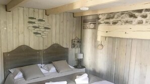 Ein Schlafzimmer mit einem hölzernen Kopfende, einem Bett mit weißen Leinentüchern und einer Steinwand.