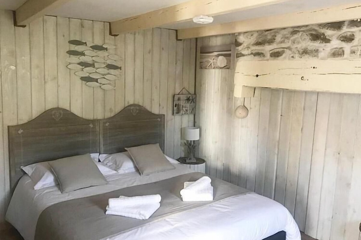 Ein Schlafzimmer mit einem hölzernen Kopfende, einem Bett mit weißen Leinentüchern und einer Steinwand.