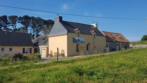 Eine Reihe von Gebäuden mit unterschiedlichen Architekturstilen, darunter ein Steinhaus mit Ziegeldach und ein gelbes Gebäude mit einem Schild.