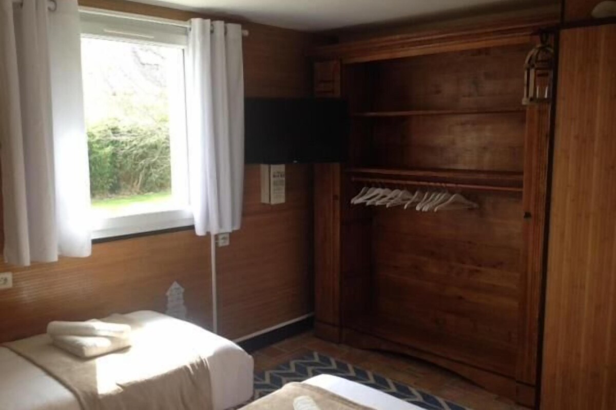 Ein Zimmer mit einem Bett, einem Holzschrank, einem Fenster mit Vorhängen und einem Fernseher.
