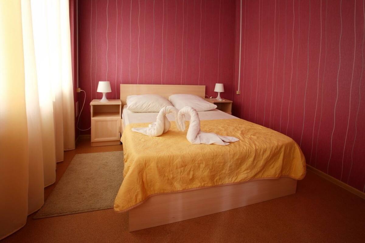 A hotel room with a bed, two bedside tables, and a nightstand.