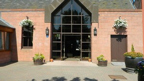 Un bâtiment doté d’une grande entrée vitrée, d’une façade en briques et de deux jardinières de chaque côté.