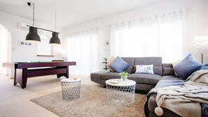 A modern living room with a pool table, grey sofa, and two pendant lights. - Villa Sapphire (Paphos)