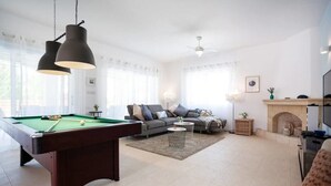A living room with a pool table, sofa, and fireplace. - Villa Sapphire (Paphos)