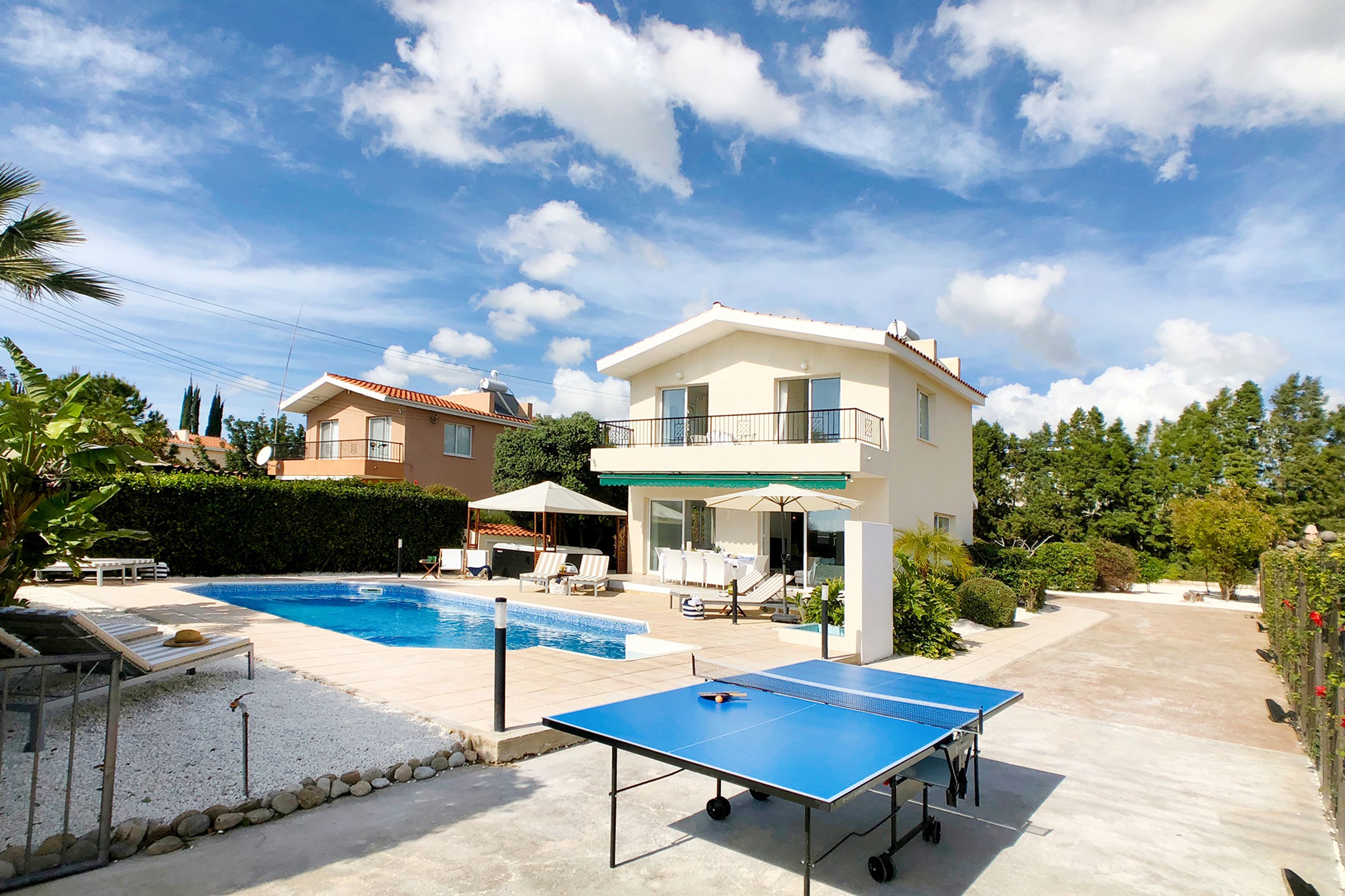 A pool area with a ping pong table, lounge chairs, and a swimming pool.
