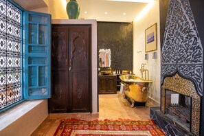 A traditional interior with a large wooden door, a bathtub, and a patterned wall. - Riad Khalifa (Marrakech)