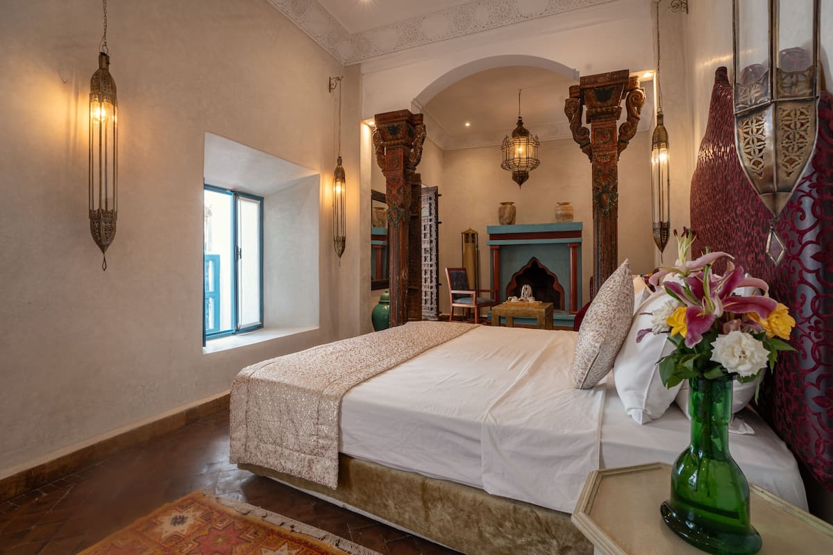 Een slaapkamer met een groot bed, een groene vaas met bloemen en decoratieve wandversieringen.